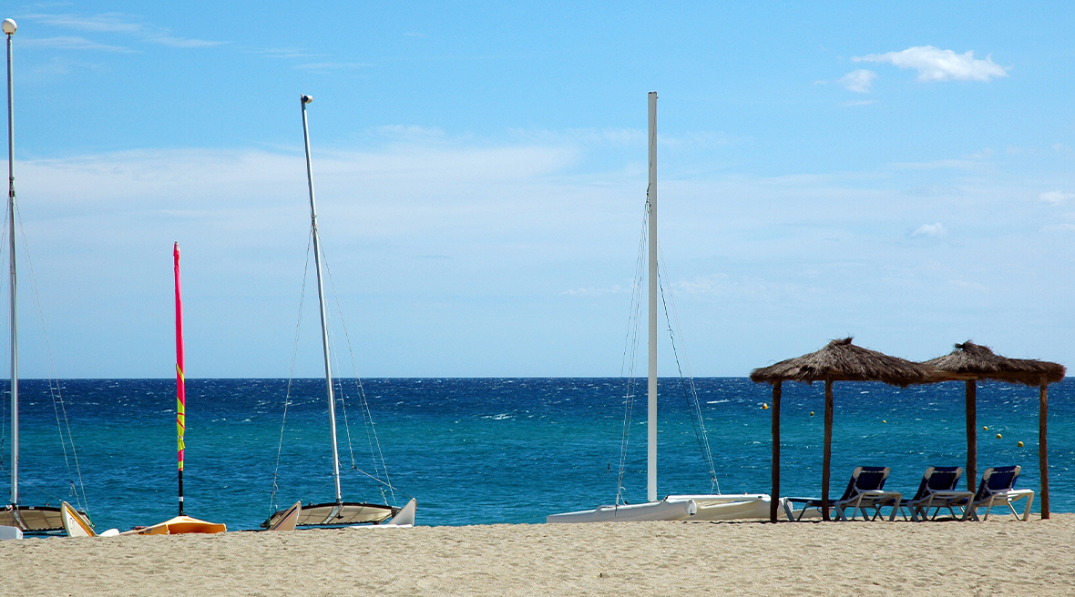 Some catamarans and sun loungers on a fine white sand beach, looking out to the blue sea